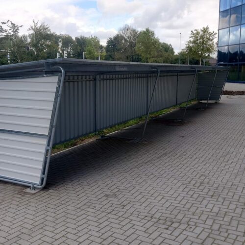 Fietsoverkapping Karin 34 Deze staat in Den Bosch. Overkapping Karin met achterwand en zijwanden. Voordelig droog fietsparkeren. Totale lengte ca 17 meter.